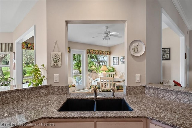 kitchen featuring stone counters, sink, and ceiling fan