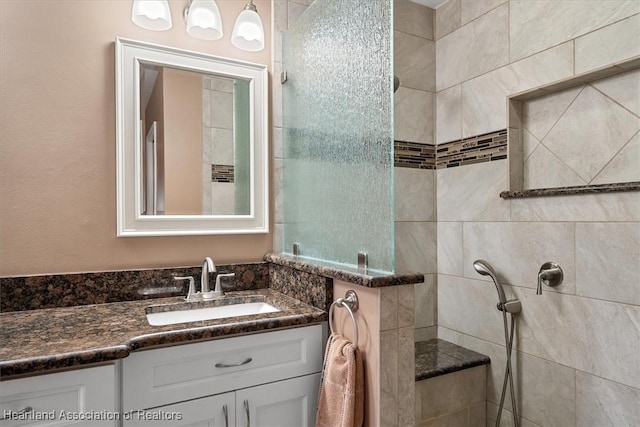 bathroom with a tile shower and vanity