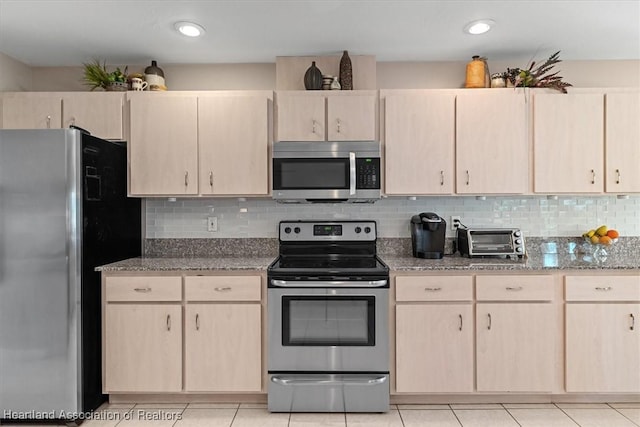 kitchen with light tile patterned floors, backsplash, stainless steel appliances, light stone counters, and light brown cabinets