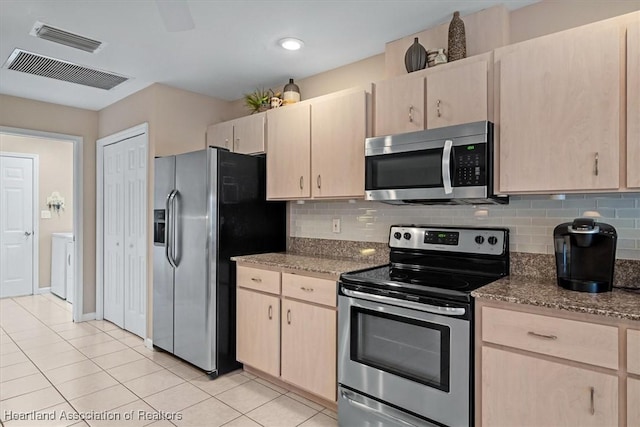 kitchen with appliances with stainless steel finishes, stone countertops, and light brown cabinets