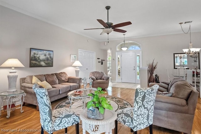 living room with crown molding, ceiling fan with notable chandelier, and light wood-type flooring