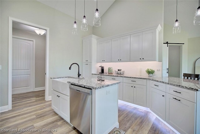 kitchen featuring white cabinets, dishwasher, a center island with sink, and a barn door