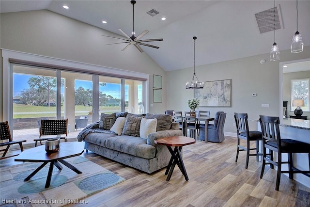 living room featuring a notable chandelier, high vaulted ceiling, and light hardwood / wood-style flooring