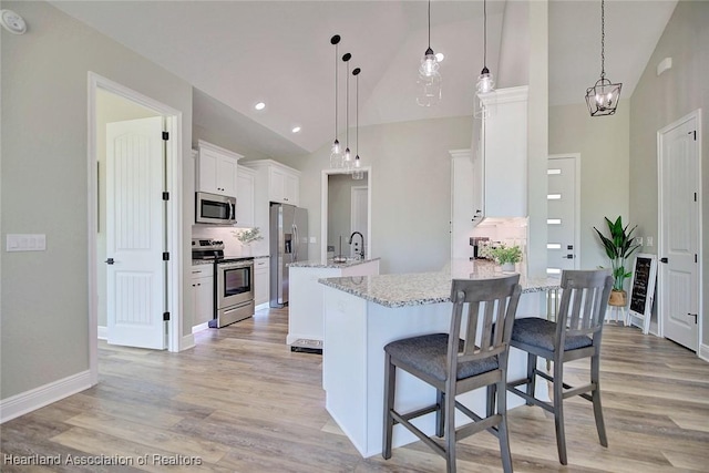 kitchen featuring light stone counters, hanging light fixtures, white cabinets, and stainless steel appliances