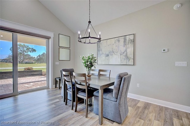 dining room featuring a chandelier, light hardwood / wood-style floors, and lofted ceiling