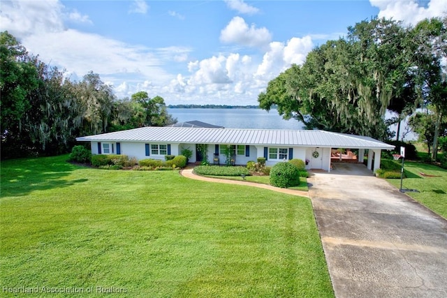 ranch-style house with a carport, a water view, and a front yard