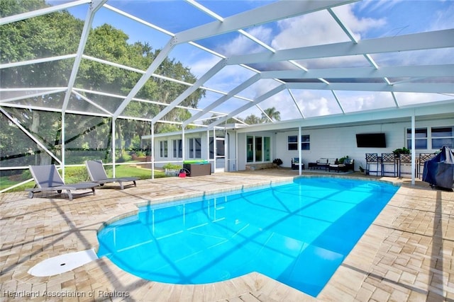 view of swimming pool with a patio area and a lanai