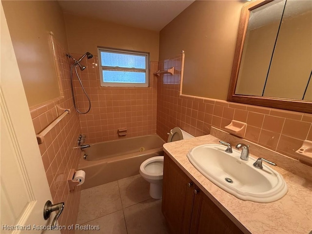 full bathroom featuring tile patterned floors, vanity, tiled shower / bath combo, tile walls, and toilet