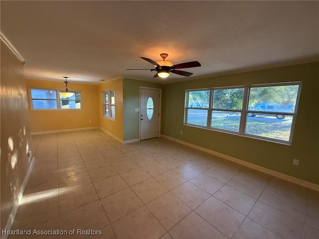 entryway with light tile patterned floors, plenty of natural light, ceiling fan, and crown molding