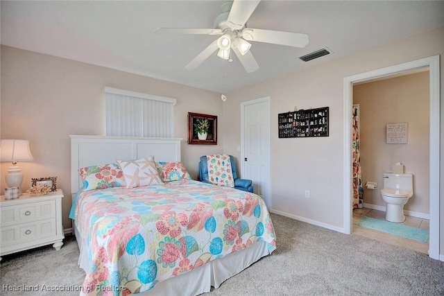 carpeted bedroom with ensuite bath and ceiling fan