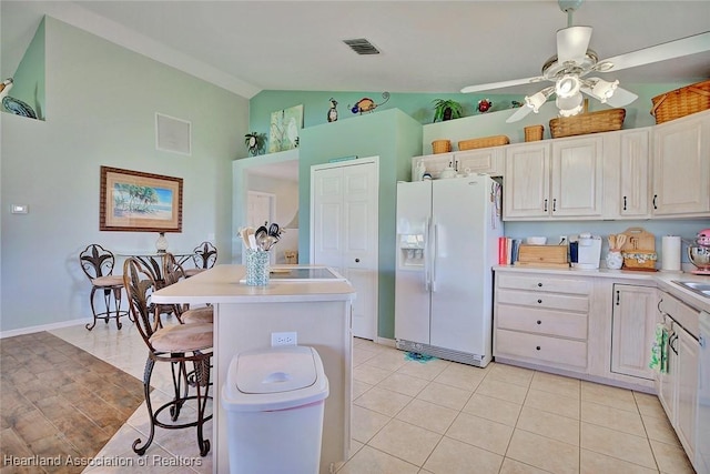 kitchen featuring a kitchen breakfast bar, vaulted ceiling, light tile patterned floors, a kitchen island, and white fridge with ice dispenser