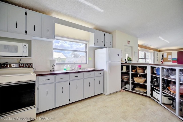 kitchen featuring white cabinetry, sink, plenty of natural light, a textured ceiling, and white appliances