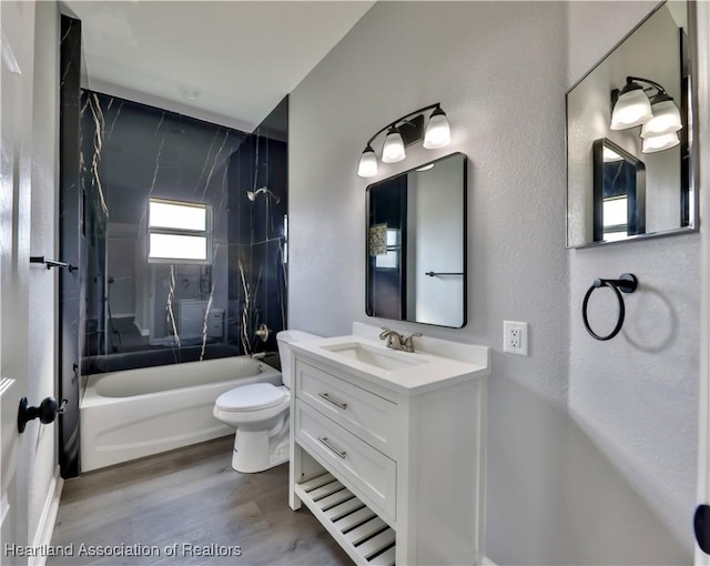 full bathroom featuring tiled shower / bath, vanity, toilet, and wood-type flooring