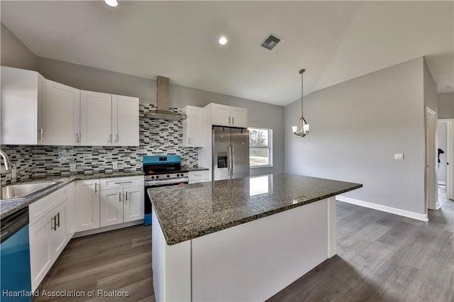 kitchen with sink, white cabinets, a center island, stainless steel appliances, and wall chimney range hood