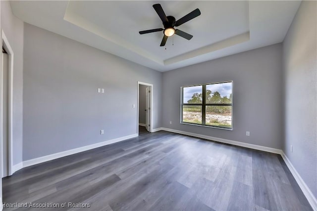 spare room with a raised ceiling, dark hardwood / wood-style floors, and ceiling fan