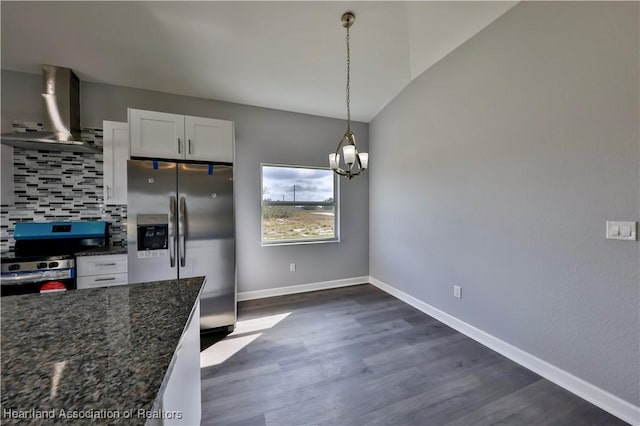 kitchen with appliances with stainless steel finishes, pendant lighting, white cabinetry, dark stone counters, and wall chimney exhaust hood