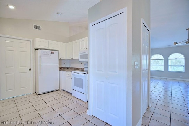 kitchen with light tile patterned flooring, white appliances, lofted ceiling, and white cabinets