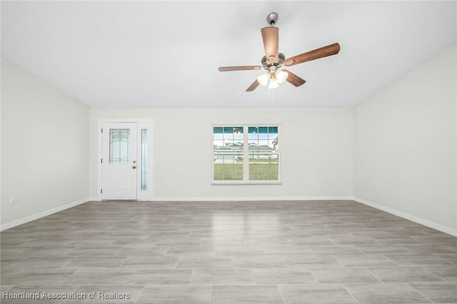 unfurnished room with baseboards, vaulted ceiling, and a ceiling fan