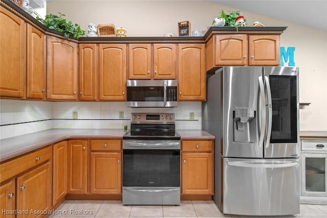 800 Spring Blvd, Sebring, FL 33876 - kitchen featuring stainless steel appliances, light tile patterned flooring, brown cabinets, and vaulted ceiling