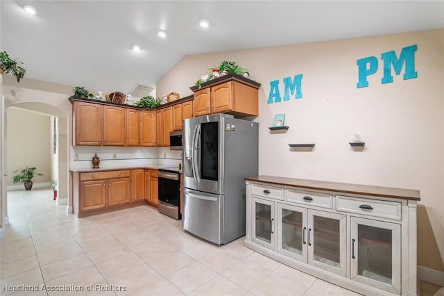 800 Spring Blvd, Sebring, FL 33876 - kitchen featuring appliances with stainless steel finishes, lofted ceiling, arched walkways, light tile patterned floors, and brown cabinets