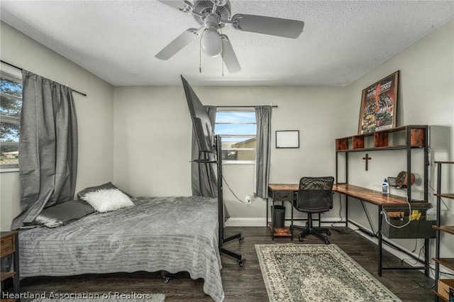 bedroom with a textured ceiling, ceiling fan, and dark wood-type flooring