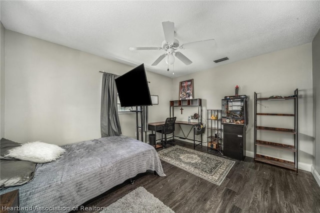 bedroom with a textured ceiling, ceiling fan, and dark hardwood / wood-style floors