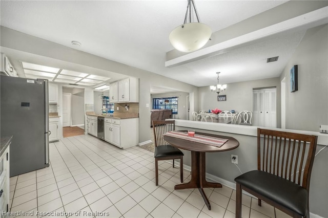 kitchen with appliances with stainless steel finishes, backsplash, decorative light fixtures, and white cabinetry