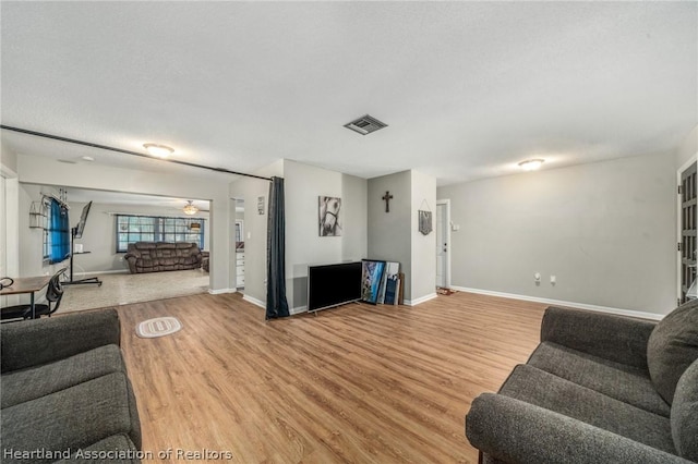 living room with ceiling fan, wood-type flooring, and a textured ceiling