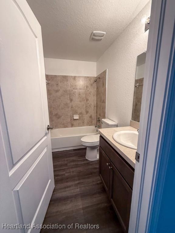525 Central Ln, Frostproof, FL 33843 - full bathroom featuring a textured ceiling, a textured wall, wood finished floors, vanity, and toilet