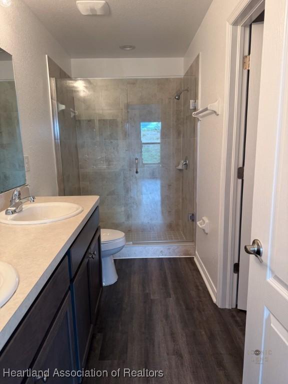 525 Central Ln, Frostproof, FL 33843 - bathroom with wood finished floors, a stall shower, double vanity, and toilet
