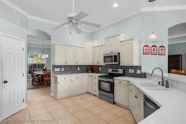 kitchen with tasteful backsplash, hanging light fixtures, stainless steel appliances, ornamental molding, and sink