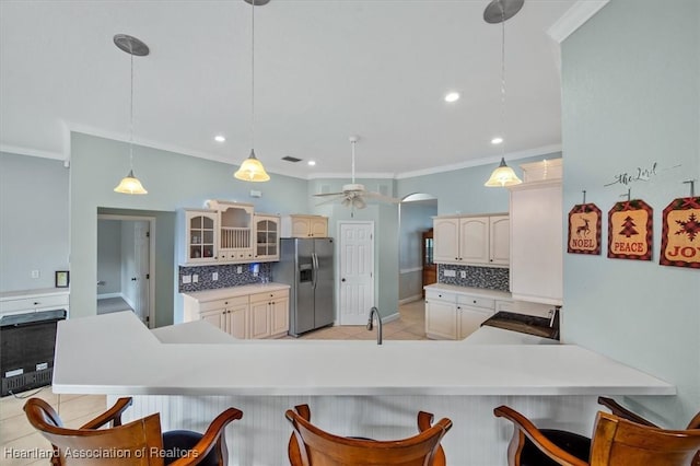 kitchen featuring a kitchen breakfast bar, pendant lighting, stainless steel fridge, ornamental molding, and kitchen peninsula