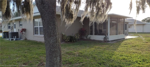 view of property exterior featuring a lawn, a sunroom, and central AC unit