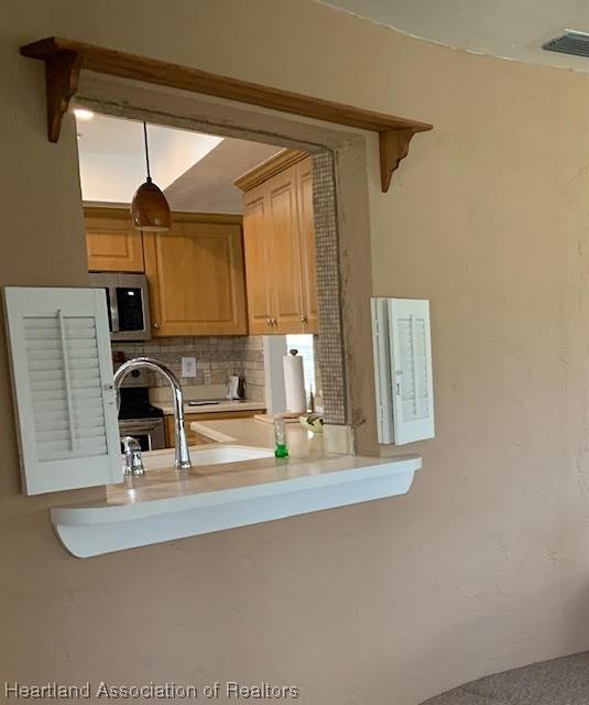 kitchen featuring decorative backsplash, light brown cabinets, and sink