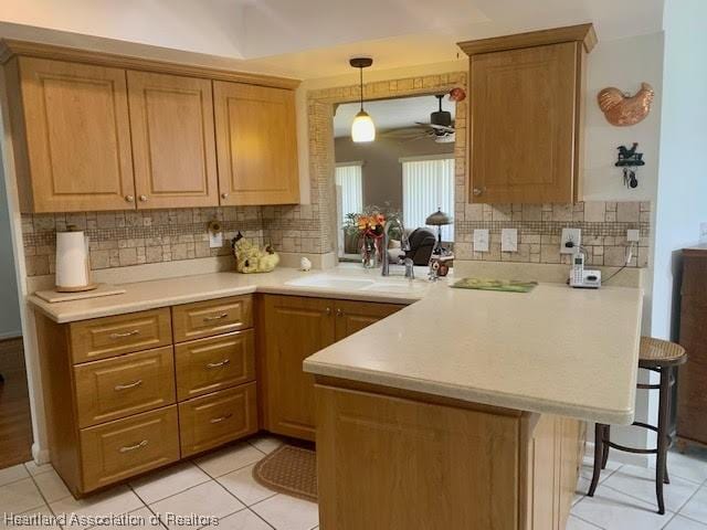 kitchen featuring ceiling fan, kitchen peninsula, a breakfast bar area, and light tile patterned floors