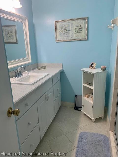 bathroom featuring tile patterned flooring, vanity, and a shower with shower door