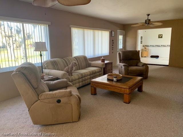 living room with ceiling fan and light colored carpet