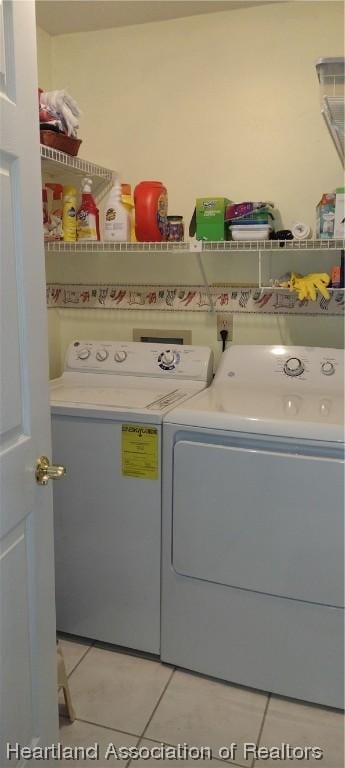 laundry area with light tile patterned flooring and washer and dryer