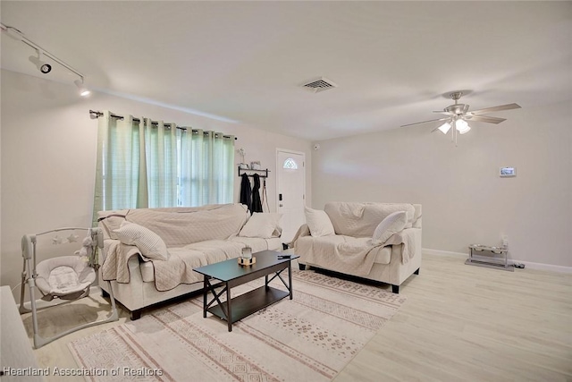 living room with light wood-type flooring, rail lighting, and ceiling fan
