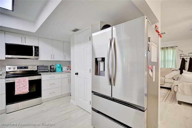 kitchen featuring white cabinets, appliances with stainless steel finishes, and light wood-type flooring