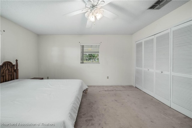 carpeted bedroom featuring ceiling fan, a closet, and a textured ceiling