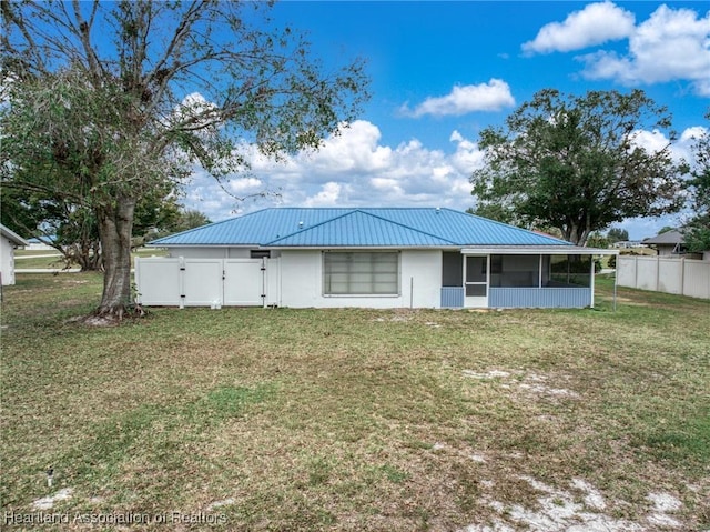 back of property with a sunroom and a yard