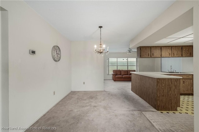 kitchen with sink, an inviting chandelier, decorative light fixtures, light carpet, and kitchen peninsula