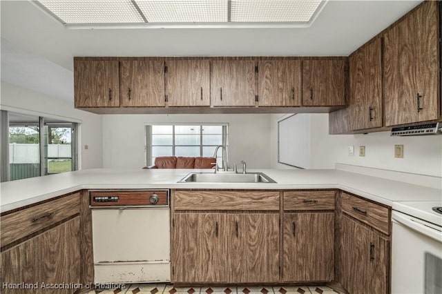 kitchen with white electric range oven, kitchen peninsula, and sink