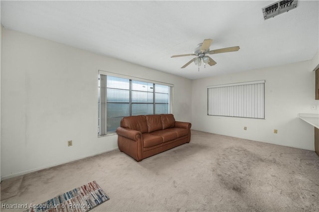 living area featuring light colored carpet and ceiling fan