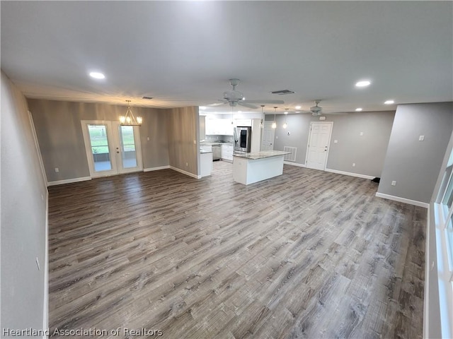 unfurnished living room featuring hardwood / wood-style floors and ceiling fan with notable chandelier