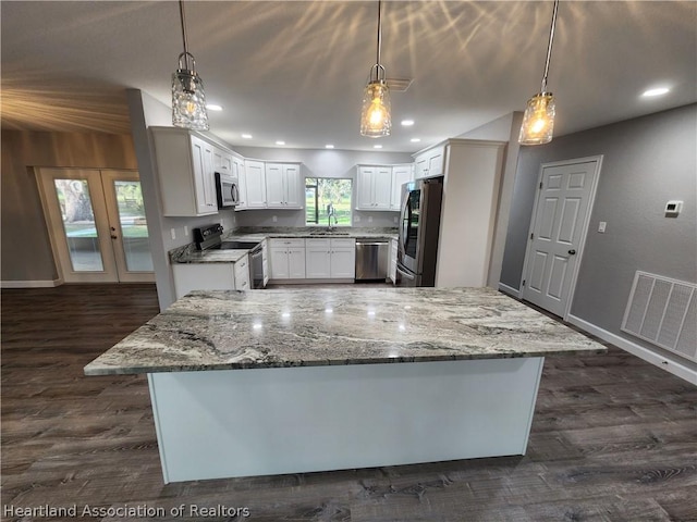 kitchen featuring white cabinets, decorative light fixtures, stainless steel appliances, and light stone counters