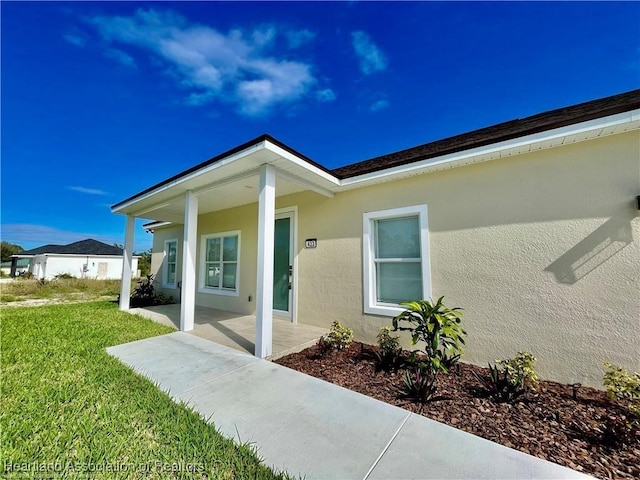 1408 Washington Blvd NE, Lake Placid, FL 33852 - view of exterior entry featuring stucco siding and a lawn