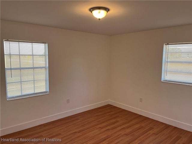 spare room with wood-type flooring and a healthy amount of sunlight