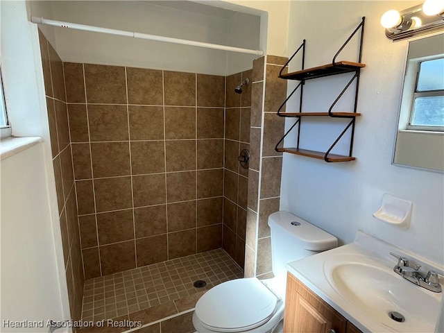 bathroom with toilet, vanity, and tiled shower